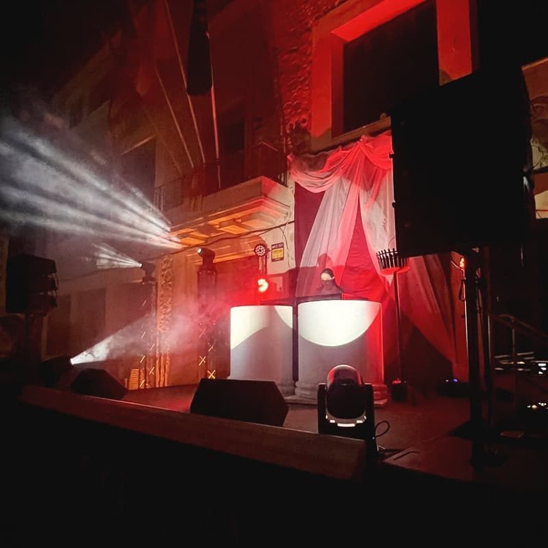 DJ auf einem Dorfplatz auf Mallorca mit Lichtstrahlen, Nebel und Bühnenbeschallung