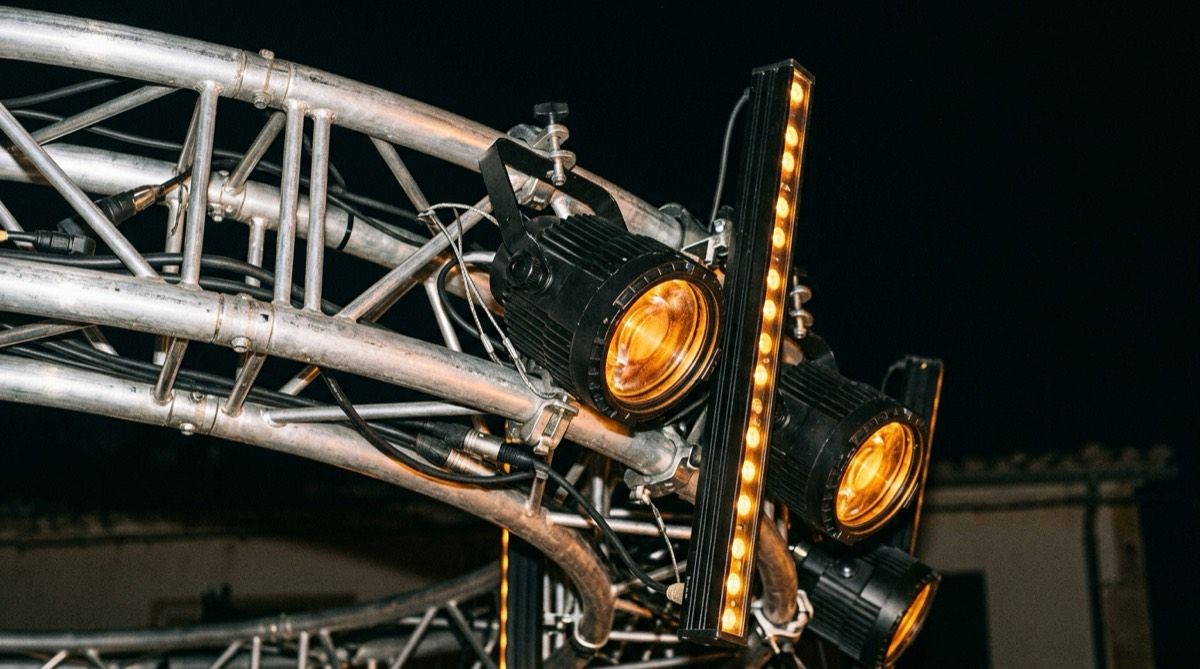 LED PAR cans and LED battens clamped to an aluminium truss, lenses glowing amber